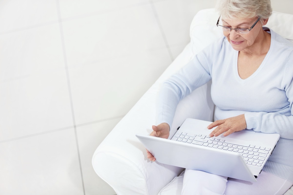 An older woman calmly checking a number on her laptop at home
